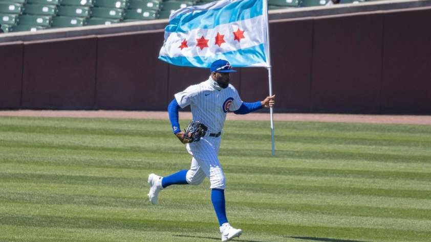 Jason Heyward running with the city of Chicago's flag across a baseball outfield.