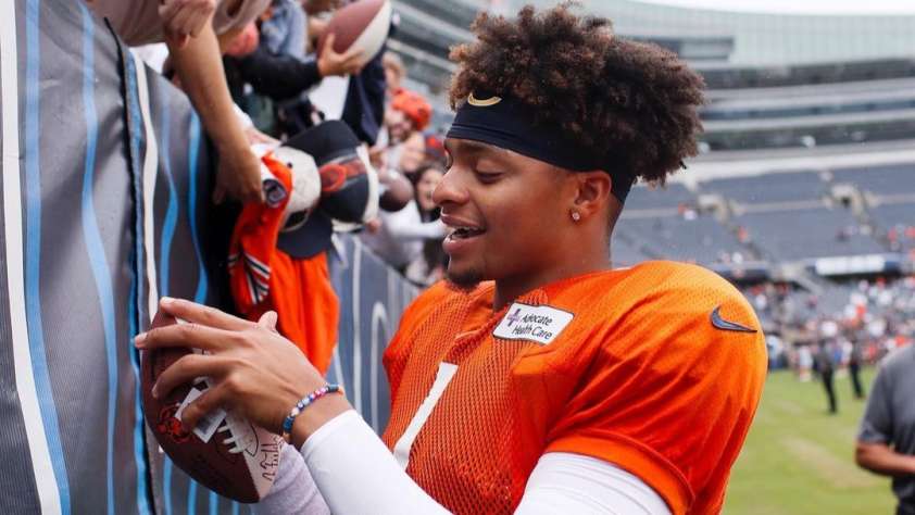 2023 Fantasy Football post featured image of Bear's QB Justin Fields autographing a fan's football.