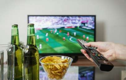 Watching football game on TV with snacks on the table