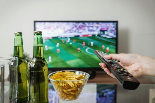Watching football game on TV with snacks on the table