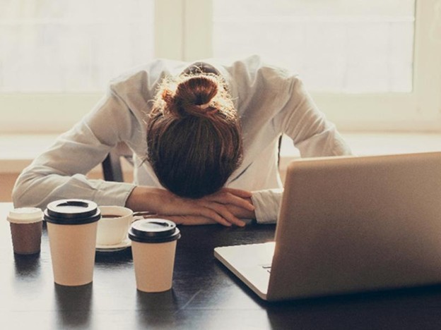 Woman with a lot of coffee fatiqued resting on table