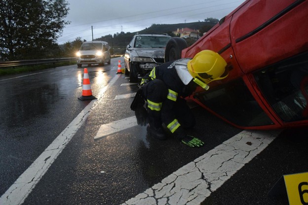 Emergency responder inspecting an overturned vehicle after a serious Los Angeles car accident on a rainy road